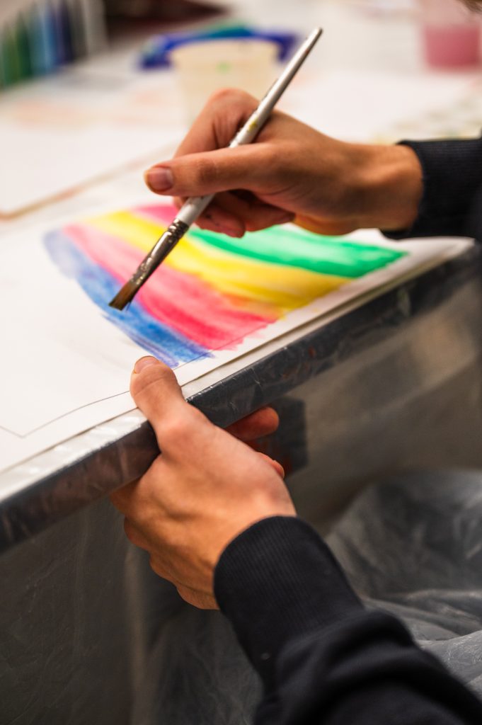 Painting of someone painting a rainbow