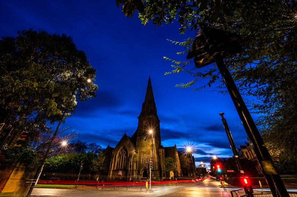 Photograph of traffic with light trails, passing by a church and Gudwara in Sunderland