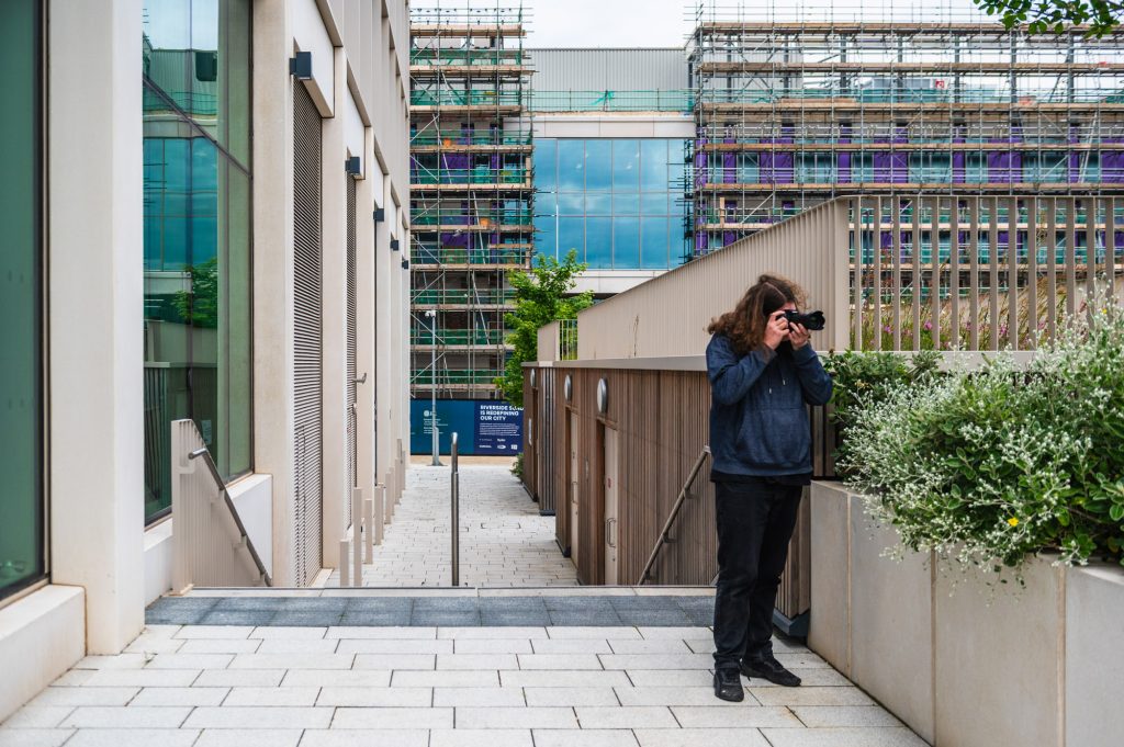 Photograph of a man taking photographs of buildings in an architectural setting