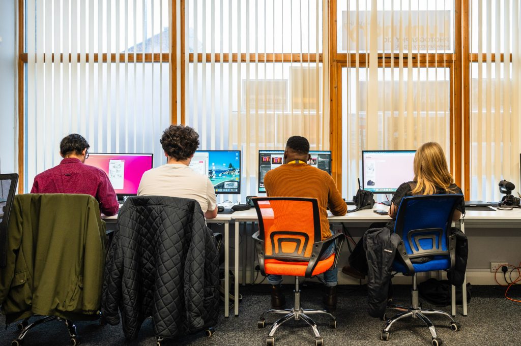 Group of people sat a t computers editing images