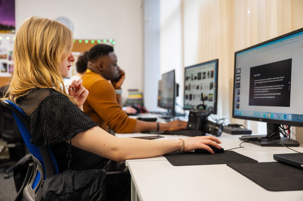 Photograph of young people, photography students, using computers to edit images.