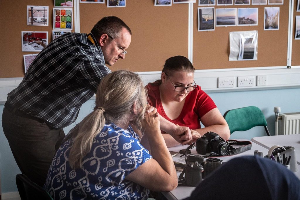 Tutor teaching two women photographers